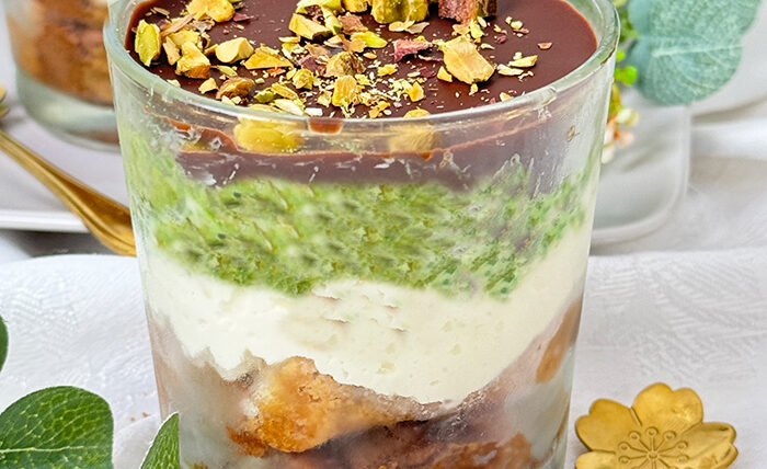 Ein kunstvoll Dubai Schokoladen Tiramisu geschichtetes Tiramisu im Glas, bestehend aus Schokoladenbiskuit, cremiger Mascarpone, Pistaziencreme und einer Schokoladenglasur, garniert mit gehackten Pistazien.