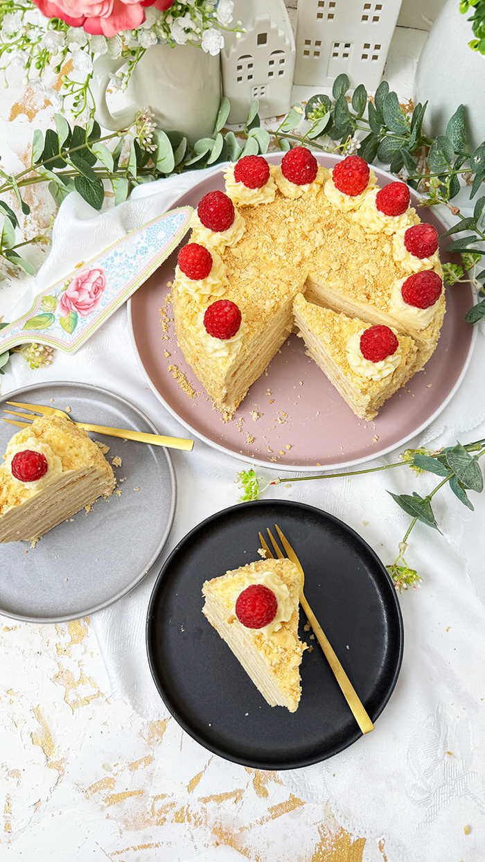 Eine Napoleon-Torte mit mehreren dünnen Schichten, die mit einer cremigen Füllung gefüllt sind und mit frischen Himbeeren dekoriert wurden