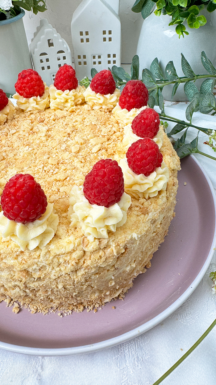 Eine Napoleon-Torte mit mehreren dünnen Schichten, die mit einer cremigen Füllung gefüllt sind und mit frischen Himbeeren dekoriert wurden