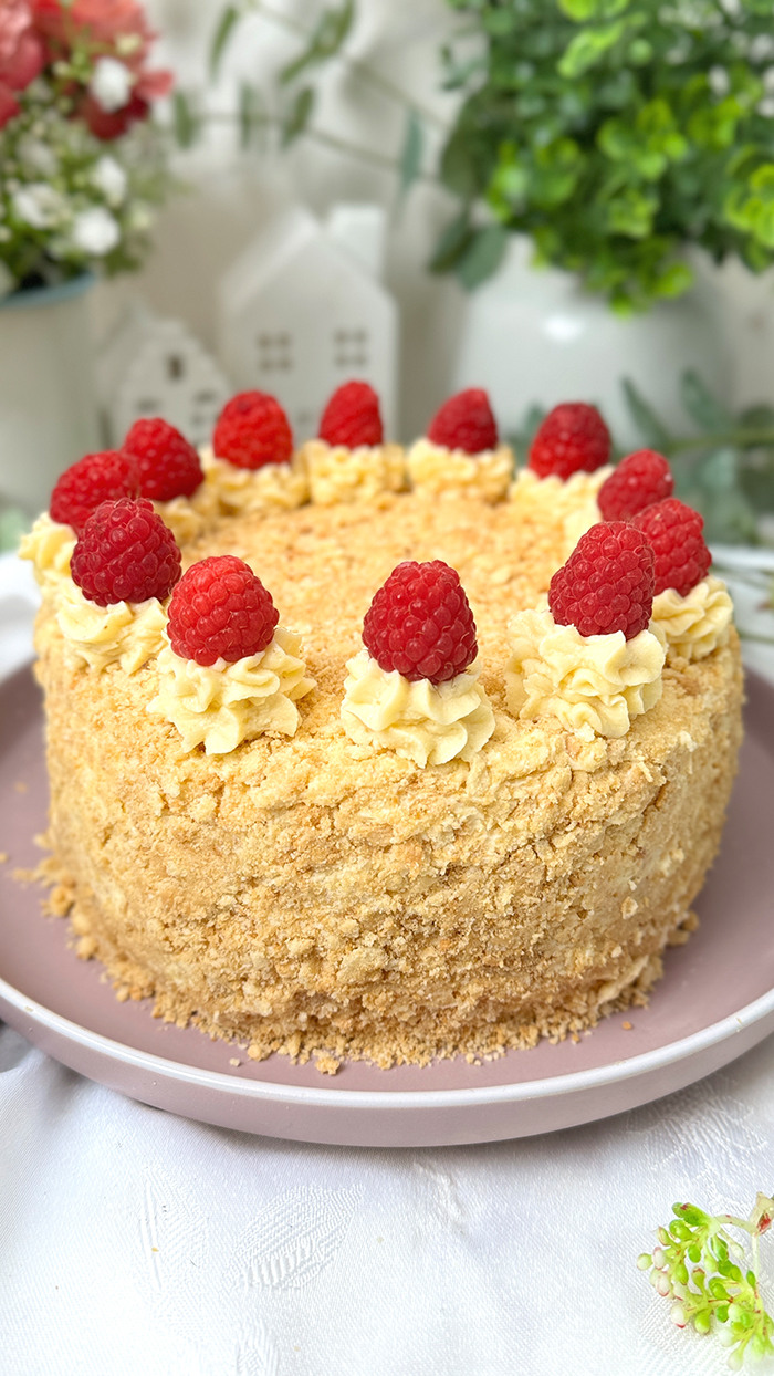 Eine Napoleon-Torte mit mehreren dünnen Schichten, die mit einer cremigen Füllung gefüllt sind und mit frischen Himbeeren dekoriert wurden