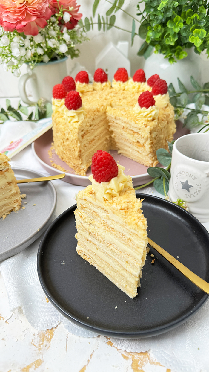 eine Napoleon-Torte mit mehreren dünnen Schichten, die mit einer cremigen Füllung gefüllt sind und mit frischen Himbeeren dekoriert wurden