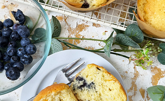 Ein Teller mit Blaubeermuffins und einer Schüssel Blaubeeren auf einem Drahtgitter