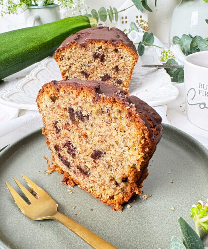 Ein saftiger Zucchinikuchen mit Schokolade, veredelt durch eine glänzende Glasur und Schokostückchen, ideal für gemütliche Kaffeepausen.