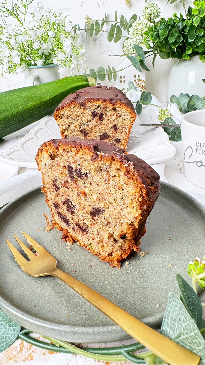 Ein saftiger Zucchinikuchen mit Schokolade, veredelt durch eine glänzende Glasur und Schokostückchen, ideal für gemütliche Kaffeepausen.