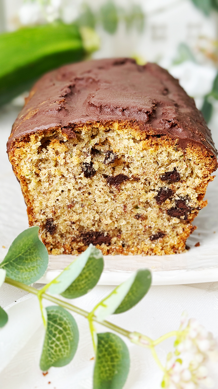 Ein saftiger Zucchinikuchen mit Schokolade, veredelt durch eine glänzende Glasur und Schokostückchen, ideal für gemütliche Kaffeepausen.