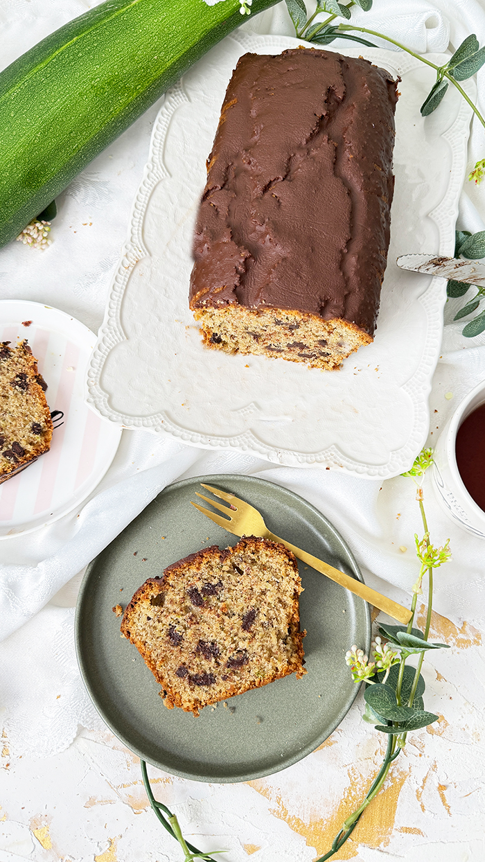 Ein saftiger Zucchinikuchen mit Schokolade, veredelt durch eine glänzende Glasur und Schokostückchen, ideal für gemütliche Kaffeepausen.